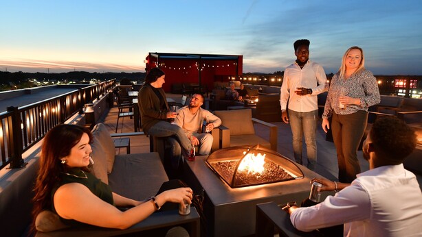 Un bar en la azotea con mesas al aire libre, una chimenea y vistas del horizonte urbano.