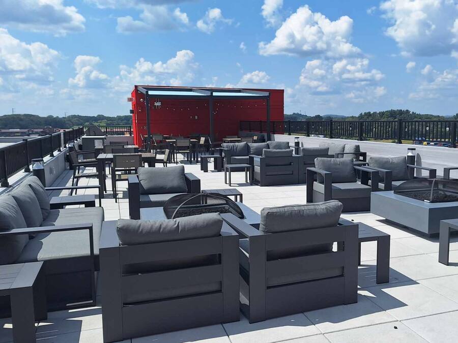 A rooftop terrace with outdoor seating, a red structure, and a view of the landscape.