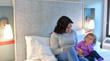 A hotel room with a bed, a bedside phone, and a wall-mounted lamp.