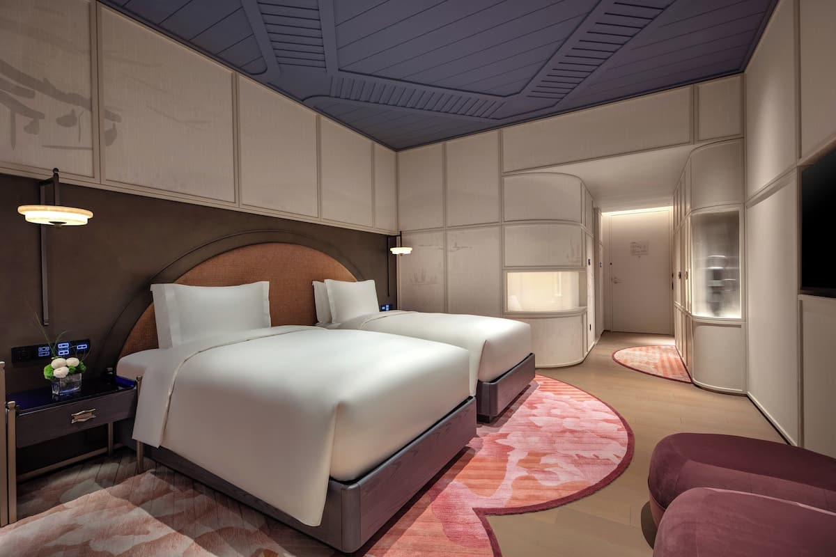 Ein modernes Hotelzimmer mit einem großen Bett, Nachttischen, einem Fernseher und einem begehbaren Kleiderschrank.