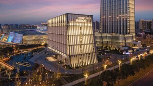Um hotel moderno com fachada de vidro, chamado "Hotel Indigo", com design contemporâneo e área de piscina no terraço.