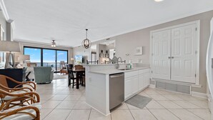 A spacious kitchen with a large island, white cabinetry, and a view to the outside. - Grande Pointe 414 | Beach, Pools, Fitness Center | My Beach Getaways (Orange Beach)