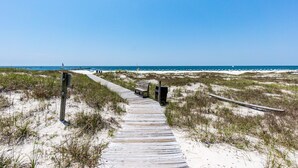 A wooden boardwalk leading to a beach with sand dunes and a clear blue sky. - Grande Pointe 414 | Beach, Pools, Fitness Center | My Beach Getaways (Orange Beach)