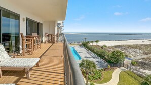 A balcony with a pool, chairs, and a view of the beach. - Grande Pointe 414 | Beach, Pools, Fitness Center | My Beach Getaways (Orange Beach)