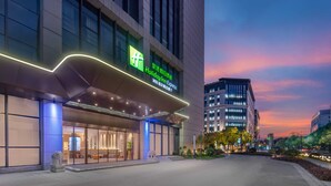 A hotel with a modern facade, large windows, and a prominent green sign. - Holiday Inn Express Shanghai Hongqiao Linkong by IHG (Shanghai)
