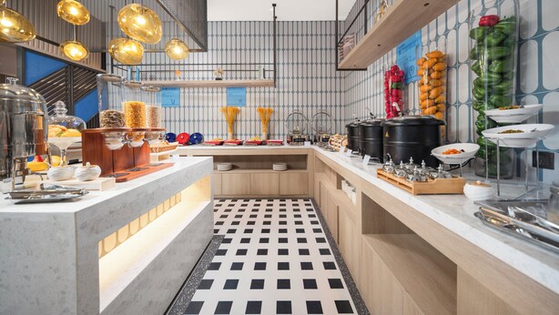 A modern kitchen with a checkered floor, stainless steel appliances, and a variety of food items displayed on the counter. - Holiday Inn Express Shanghai Hongqiao Linkong by IHG (Shanghai)