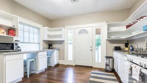 Una cocina amplia con armarios blancos, microondas, cafetera y un lavamanos de acero inoxidable.