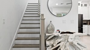 Un interior moderno con una escalera, un espejo redondo y una escultura de madera única.