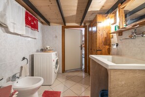 Cocina compacta con un lavamanos, lavadora y un armario de madera.
