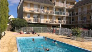 A swimming pool with people in it, surrounded by a building with balconies. - Studio Apartment 'Au Coeur De Quiberon' with Shared Pool, Balcony and Wi-Fi (Quiberon)