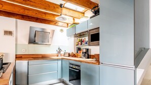 Une cuisine moderne avec des armoires bleu clair, des appareils en acier inoxydable et des poutres en bois au plafond.