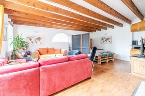A living room with a red sofa, wooden beams, a plant, and a world map on the wall.