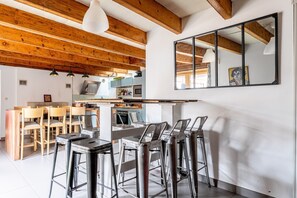 A modern kitchen with wooden beams, a bar area with stools, and a large mirror on the wall.