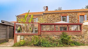 Un bâtiment en pierre avec un toit rouge, une antenne parabolique et une fenêtre à cadre rouge.