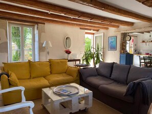 A living room with a yellow sofa, a grey sofa, a white coffee table, and a small round table.