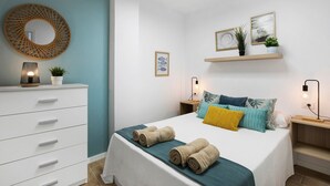 Een slaapkamer met een bed, nachtkastjes, een kaptafel, een spiegel en wandplanken met decoratieve objecten.