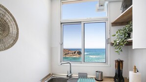Een keuken met uitzicht op de oceaan, een spoelbak, een ventilator en keukengerei.