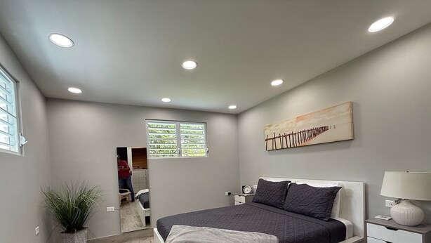 Une chambre à coucher moderne avec un lit, une table de chevet, une lampe et un tableau au mur.