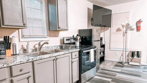 A modern kitchen with a granite countertop, stainless steel appliances, and light-colored cabinetry. - Nature's Cedar Creek Getaway-K
 (Cave Spring)