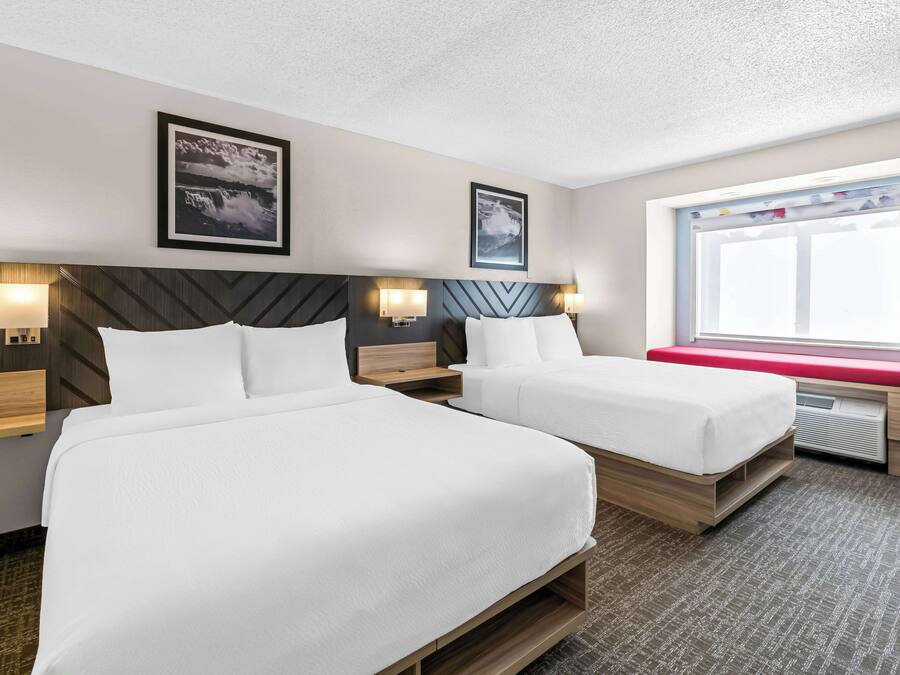 Ein Hotelzimmer mit zwei Betten, einem großen Fenster mit Blick und Kunstwerken an den Wänden.
