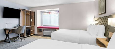 Une chambre d’hôtel avec deux lits, un bureau avec une chaise, une armoire, une télévision et une fenêtre donnant sur un paysage agréable.