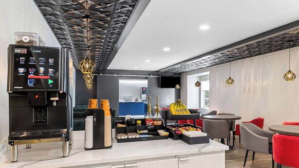 A modern coffee station with a coffee machine, a variety of coffee pods, and a selection of snacks and condiments. - Best Western Buffalo Inn & Suites (Buffalo)