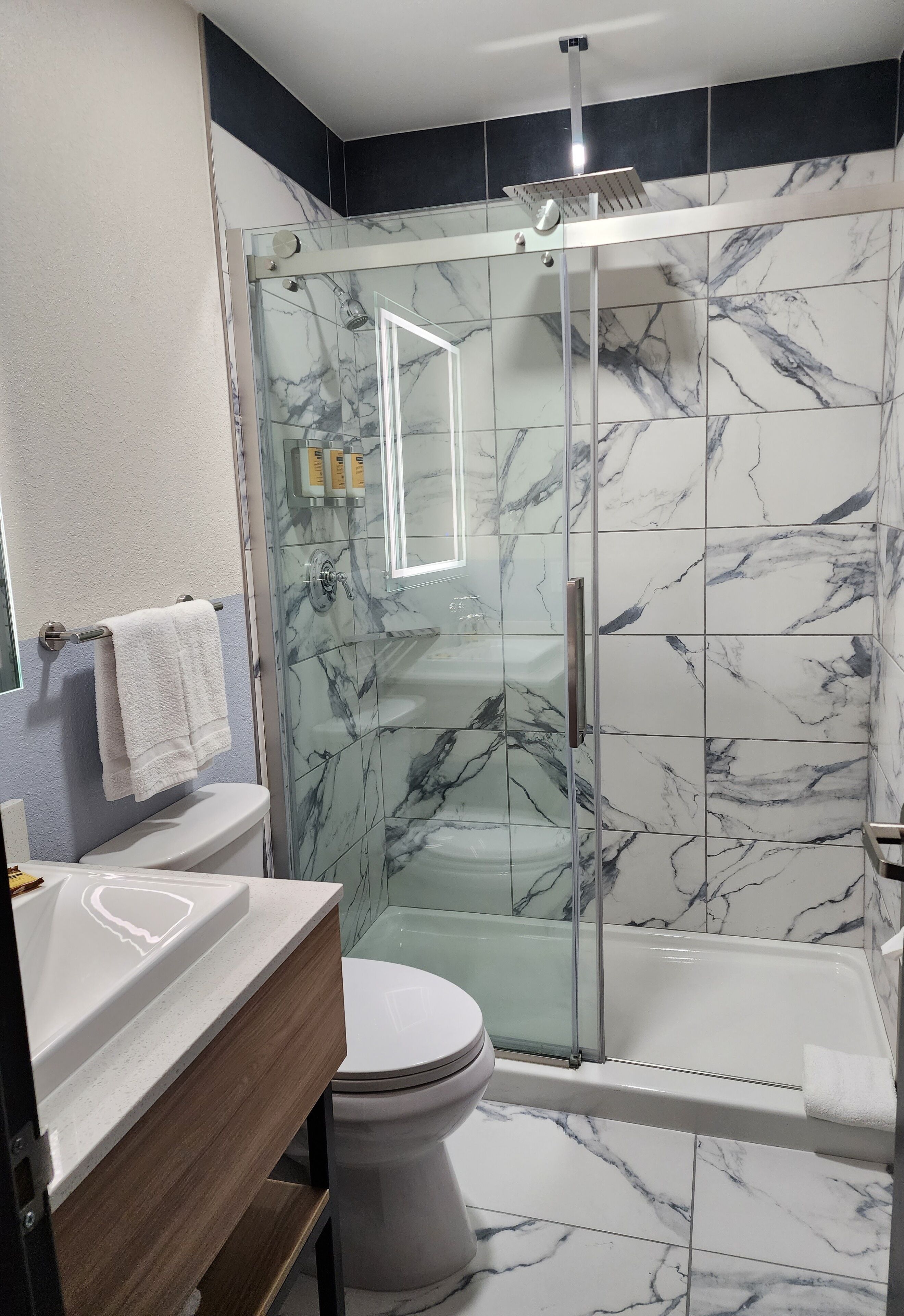 Un baño moderno con ducha envuelta en vidrio, bañera y retrete.