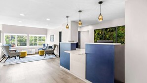 A modern reception area with a blue and white color scheme, a large window, and a green wall feature. - Best Western Buffalo Inn & Suites (Buffalo)