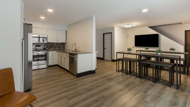 A modern kitchen with stainless steel appliances, a dining area with bar stools, and a flat-screen TV mounted on the wall. - SureStay by Best Western Camp Verde (Camp Verde)