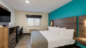 A hotel room with a bed, a desk, a chair, a television, and a window with a view of the city.