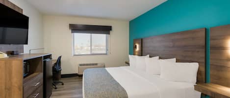 A hotel room with a bed, a desk, a chair, a television, and a window with a view of the city.