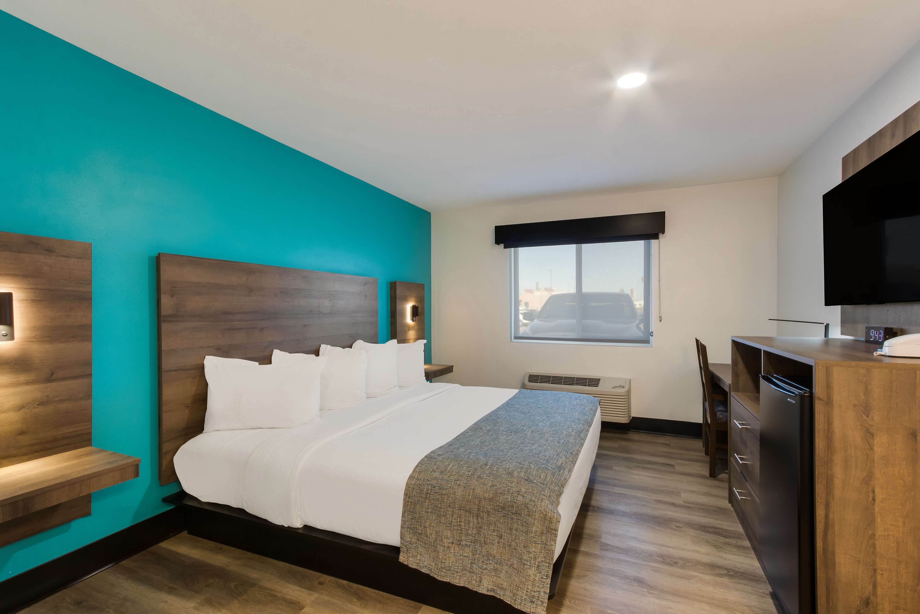 A modern hotel room with a large bed, a desk, and a TV.