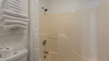 A bathroom with a toilet, a stack of white towels, and a shower area.