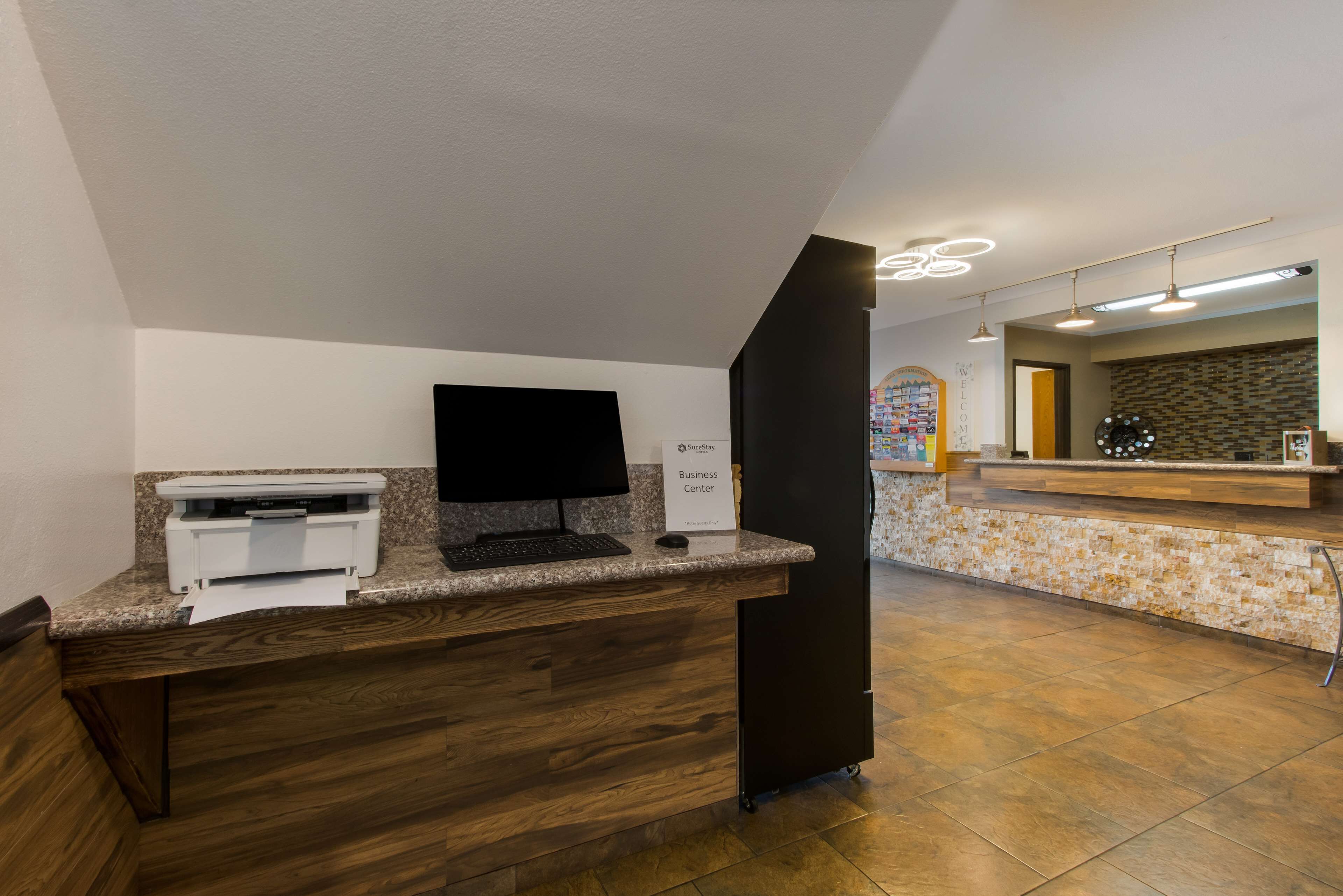 A reception desk with a flat-screen monitor, a printer, and a sign indicating a business center.