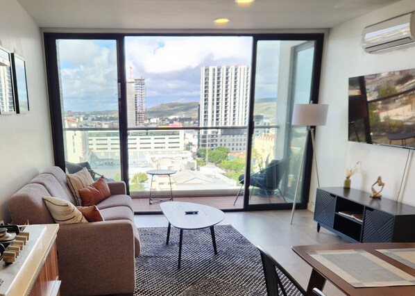Ein modernes Wohnzimmer mit einer Couch, einem Couchtisch und einem Fernseher an der Wand.