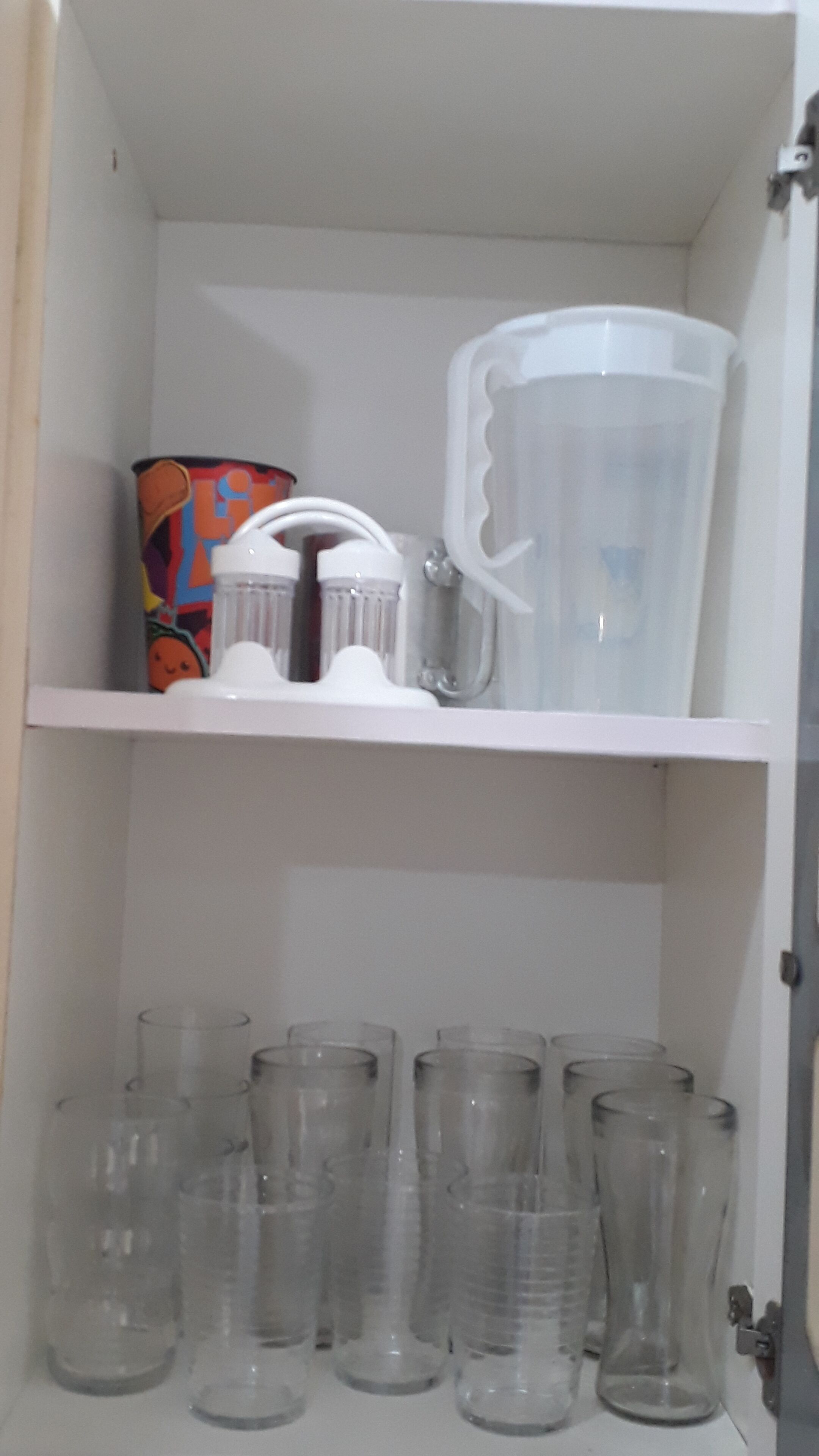 Ein Schrank mit Regalen, der verschiedene Glasbehälter und eine farbenfrohe Kiste enthält.