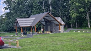 A lodge with a stone exterior and a metal roof, featuring picnic tables and a covered seating area. - Spacious Hidden Gem (Utica)