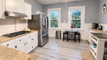 A modern kitchen with white cabinets, stainless steel appliances, a gas stove, and a ceiling fan.
