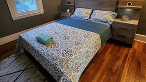 A bedroom with a bed, nightstands, a window, and a view of the outdoors. - Spacious Hidden Gem (Utica)