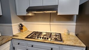 A kitchen with white cabinets, a gas stove, and a granite countertop. - Spacious Hidden Gem (Utica)