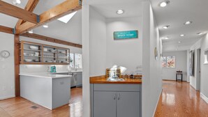 Une cuisine moderne dotée d’un îlot central, de poutres en bois et d’une enseigne accueillante.