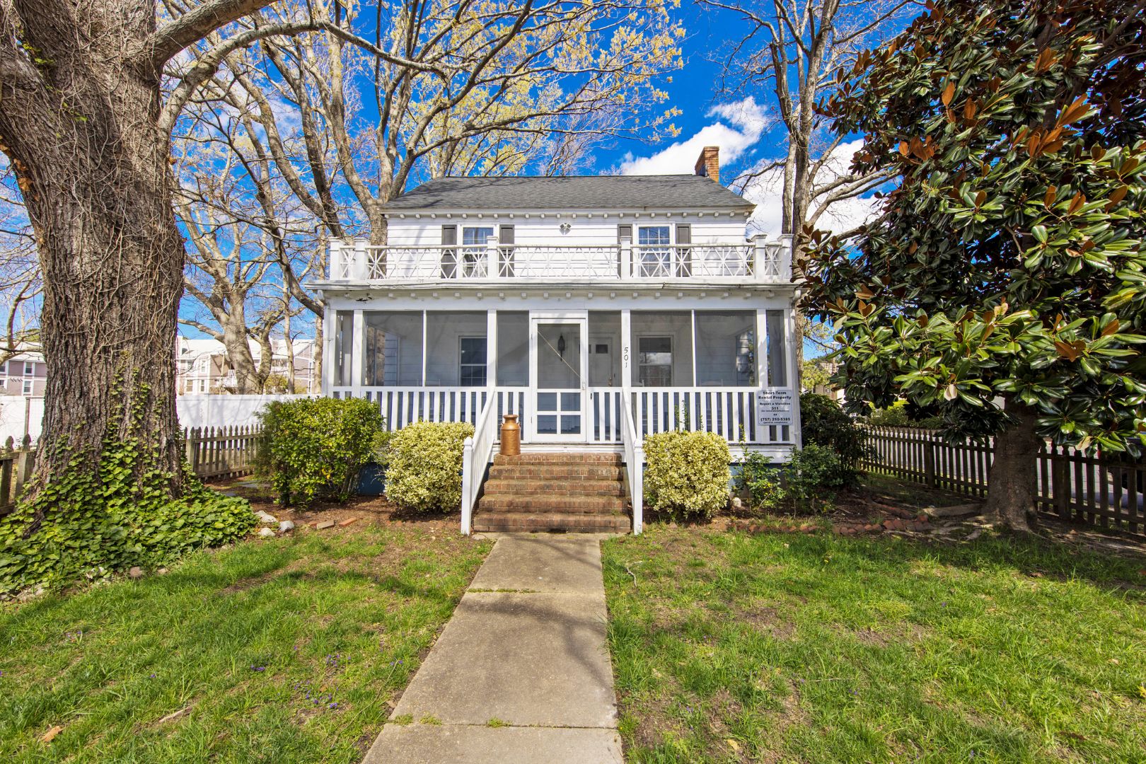 A two-story house with a front porch, a covered entryway, and a small front yard.