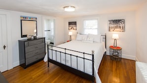 Un dormitorio con cama, cómoda, mesitas de noche y obras de arte en las paredes.