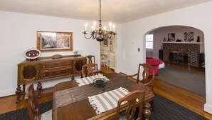 Un comedor con una mesa de madera, sillas, una araña y una chimenea.