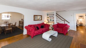 Una sala de estar con un sofá rojo, una mesa de centro blanca y una estantería.