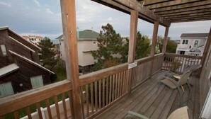 A wooden deck with a railing, a covered area, and a view of neighboring houses. - A Wave From It All - Croatan VB (Virginia Beach)
