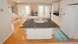 A kitchen with white cabinets, a granite countertop, and a refrigerator. - A Wave From It All - Croatan VB (Virginia Beach)