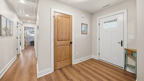 Un couloir doté d’un plancher en bois, de murs blancs et d’une porte avec une fenêtre.
