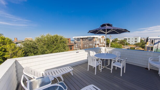 A rooftop deck with outdoor furniture, including a table and chairs, and a large umbrella. - Fairbanks House with beach access just steps from your front door (Virginia Beach)