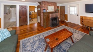 Ein Wohnzimmer mit Kamin, grünen Sofas, einem Holztisch und einem gemusterten Teppich.